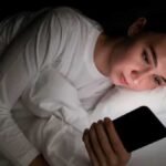 सोने से पहले मोबाइल बंद करता व्यक्ति