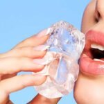 चेहरे पर बर्फ रगड़ती हुई महिला।